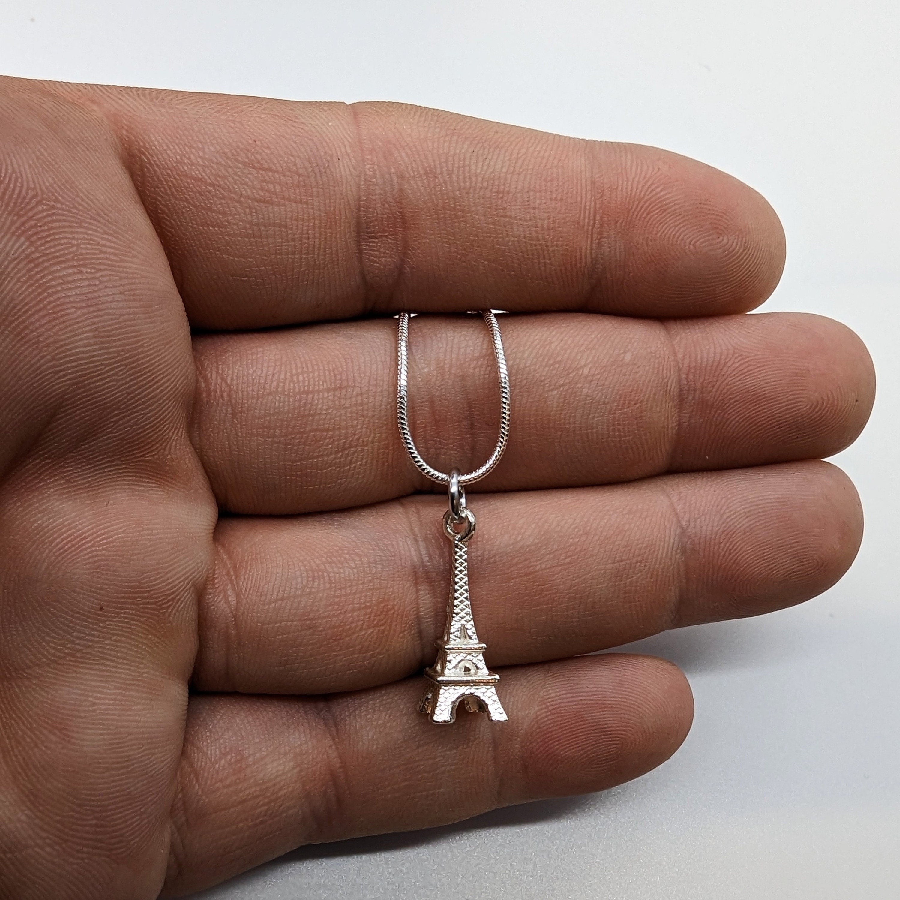 Eiffel Tower Silver Necklace Displayed on a Hand